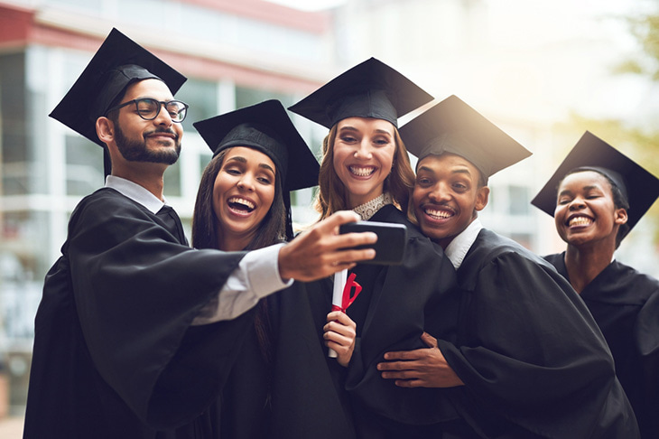 A group of graduates huddle together for a photo together