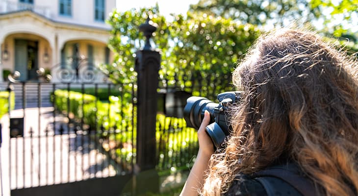 A sightseer takes a picture of a home in the Garden District of New Orleans