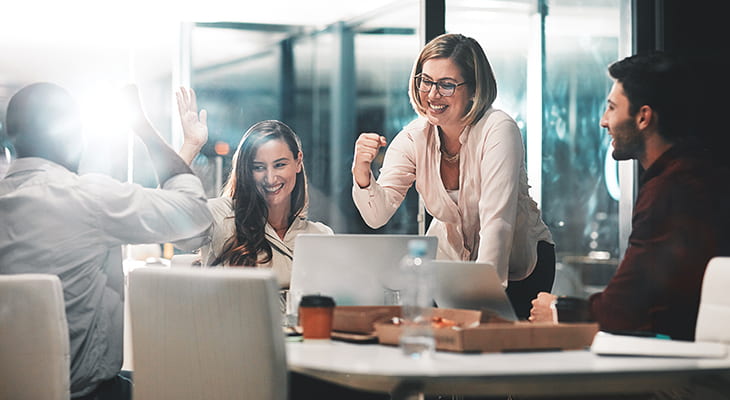 Coworkers smile and clap in a conference room