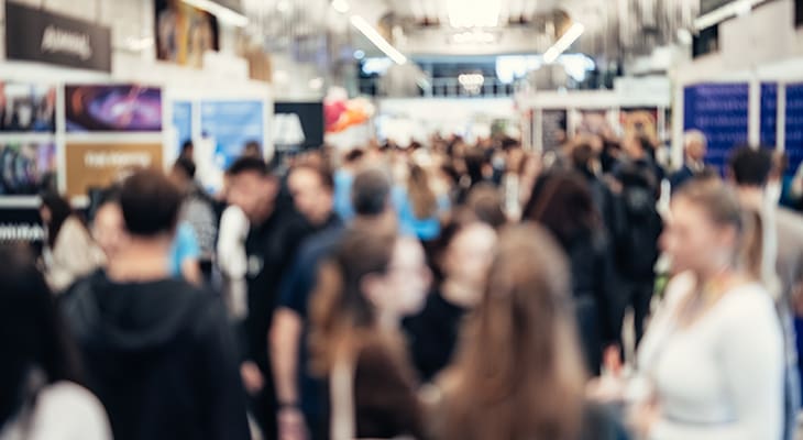 A crowd of convention attendees walk in a hall