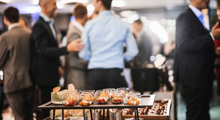 A buffet at a business event, a crowd of attendees in the background