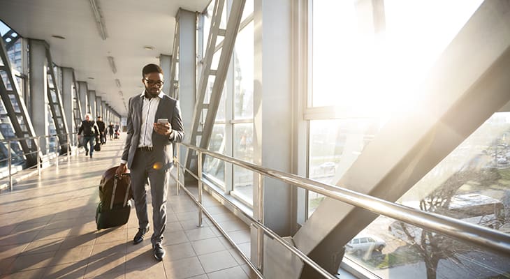 A traveler with a suitcase walks in an airport terminal