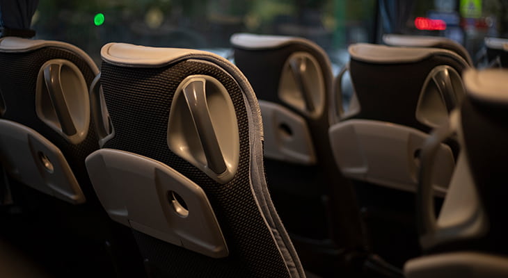 Interior of a charter bus at dusk, with interior lights on