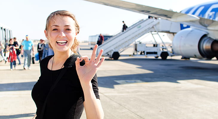 A traveler steps off an airplane and smiles