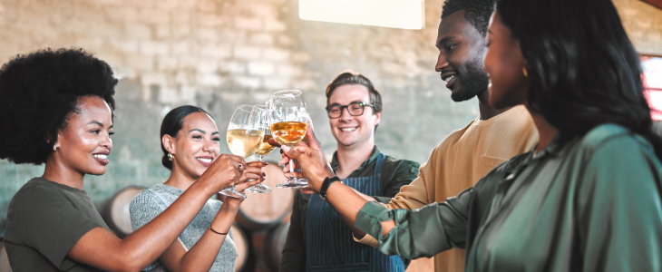 four friends laugh and toast glasses of wine